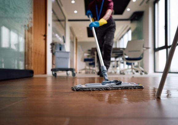Close up of professional cleaner polishing floor surfaces with a mop.